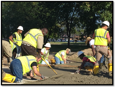 Men and women in safety gear laying cement